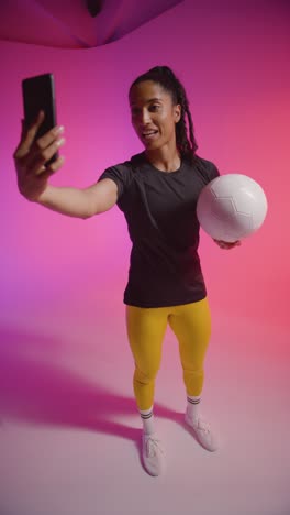 Vertical-Video-Studio-Shot-Of-Female-Footballer-Recording-Video-For-Social-Media-On-Mobile-Phone-Teaching-Ball-Skills-1